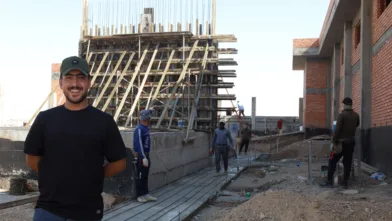 Mohammed stands with the governments new power station in the background